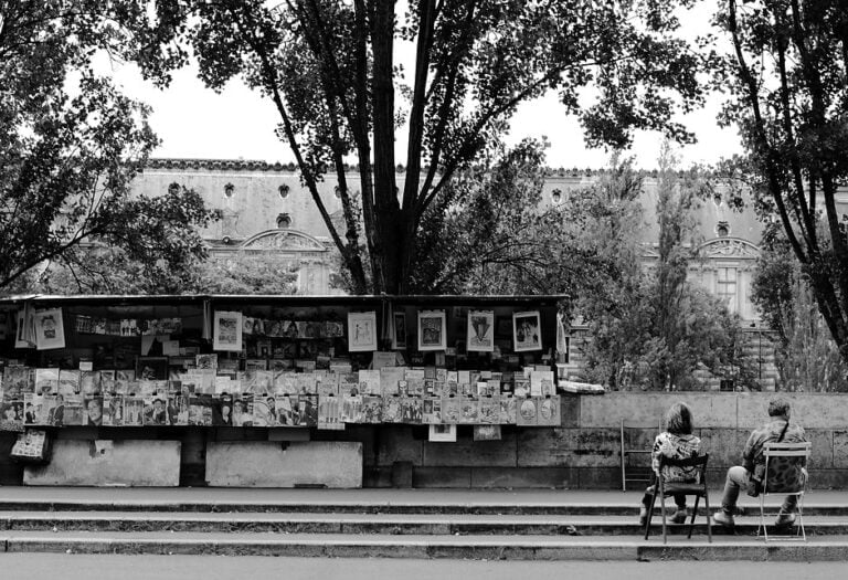 Portfolio - Capturer l'émotion authentique : Couple de bouquinistes assis sur un banc le long des quais de la Seine à Paris, photographié en noir et blanc. Une image intemporelle par le photographe de mariage de haute Garonne.