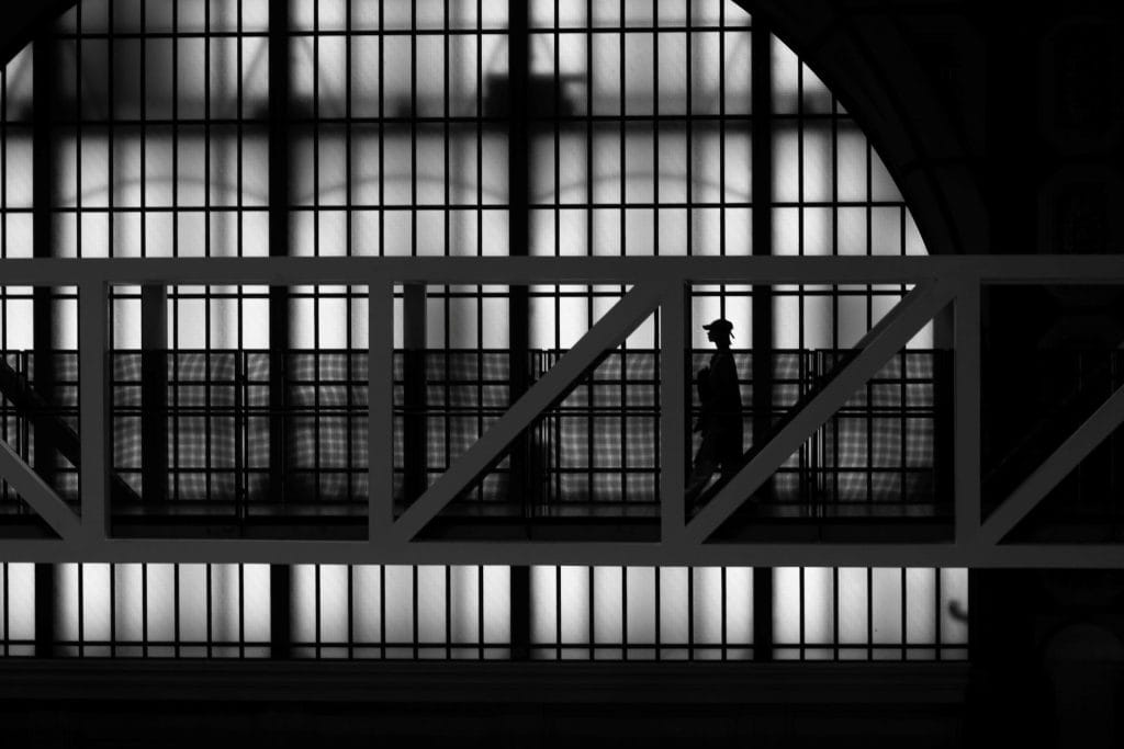 Silhouette solitaire dans une structure architecturale, série Silhouettes Parisiennes, photographie en noir et blanc de Manuel VZ